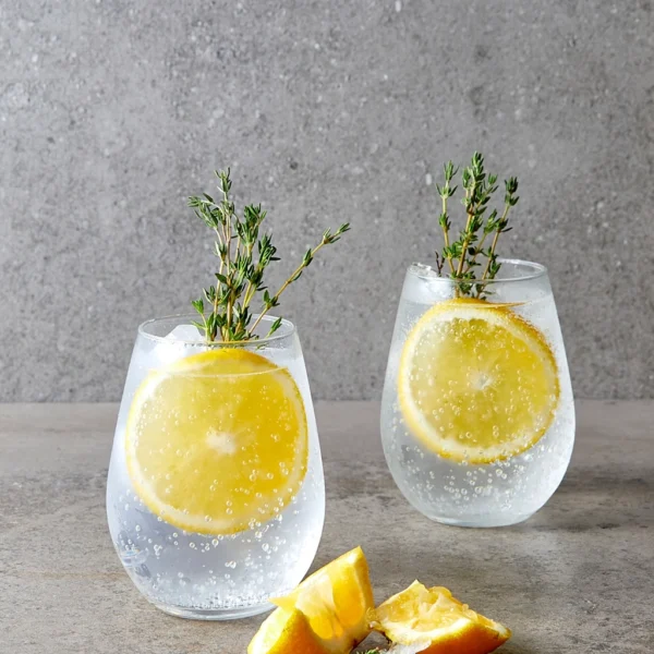 two stemless wine glass with non alcoholic lemon and herb mocktails